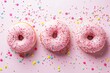 Pink Frosted Donuts Sprinkled With White Nonpareils on a Pastel Pink Surface