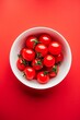Fresh Cherry Tomatoes in a White Bowl on a Red Background