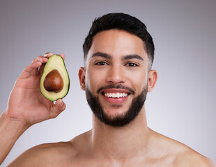 Poster - Studio, portrait and man with avocado, skincare and smile with confidence, vitamin c and collagen. Cosmetics, facial health and happy male model with fruit, dermatology or grooming on grey background