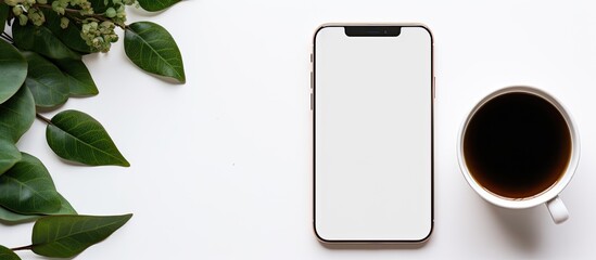 Fototapete - A white table holds a phone mockup accompanied by a cup of coffee and leaves for a more visually appealing copy space image