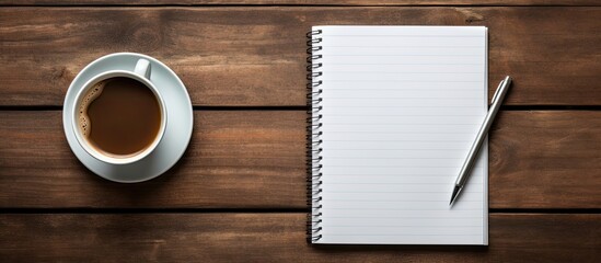 Poster - A copy space image featuring a close up view of a coffee cup pen and notebook placed on a wooden background