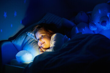 Wall Mural - Little girl reading a book in bed