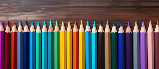 Poster - A vibrant array of color pencils arranged on a wooden table providing ample copy space image