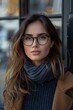 A confident young woman in glasses exudes stylish elegance outdoors, her captivating gaze speaking volumes