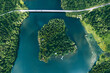 Aerial view of bridge road with car over blue water lake or sea with island  and green woods in Finland.