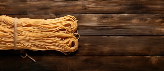 Poster - A copy space image of spaghetti tied with twine sits atop a rustic wooden table viewed from above