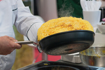 Wall Mural - Typical potato omelette. Professional cook in a professional kitchen preparing a potato omelette. Peaked potato omelette.