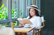 Portrait image of a beautiful young woman with hat reading book