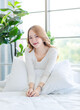 © Bangkok Click Studio - Asian beautiful woman in her bedroom on bed, feeling happy and smiling relaxed stretching arm and body after getting up from sleep on bed in bedroom at home, waking up in the morning.