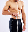 Man, results and measuring tape for diet as bodybuilder in competition, strength and wellness on studio backdrop. Healthy, male person and muscle for fitness, workout and exercise in white background