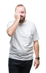 Sticker - Young caucasian hipster man wearing casual t-shirt over isolated background covering one eye with hand with confident smile on face and surprise emotion.