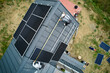 Builders measuring solar panels with tape measure. Aerial view of workers taking measurements before mounting solar modules on roof of house for generating electricity through photovoltaic effect.