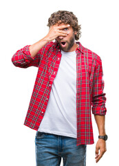 Canvas Print - Handsome hispanic model man over isolated background peeking in shock covering face and eyes with hand, looking through fingers with embarrassed expression.