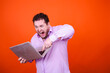 © vladorlov - Funny adult man playing games on a laptop. Orange background.