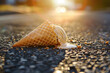 Melting ice cream cone lying on the hot asphalt. Heat wave in a city. Climate change concept.