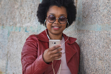 Wall Mural - urban woman with headphones and phone on the wall