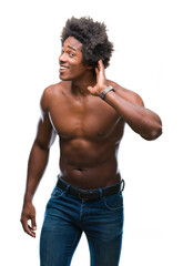 Wall Mural - Afro american shirtless man showing nude body over isolated background smiling with hand over ear listening an hearing to rumor or gossip. Deafness concept.