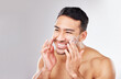 Happy Asian man, face or cream for beauty in studio with smile, natural cosmetics or glow for shine. Dermatology, antiaging product or male model applying skincare lotion or creme on white background