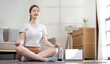 beautiful happy girl with closed eyes practicing yoga in lotus position in living room.