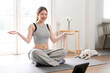 Cheerful active woman doing fitness at home,  sitting on the floor and watching online lessons on digital tablet