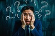 © valentyn640 - A man in a suit is looking at a chalkboard with many questions on it. He is wearing a tie and he is in a state of confusion or worry. Concept of uncertainty and the need for answers or solutions