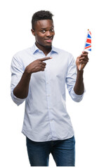 Poster - Young african american man holding United Kingdom flag very happy pointing with hand and finger