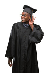 Poster - Young graduated african american man over isolated background smiling with hand over ear listening an hearing to rumor or gossip. Deafness concept.