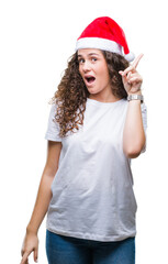 Wall Mural - Young brunette girl wearing christmas hat over isolated background pointing finger up with successful idea. Exited and happy. Number one.