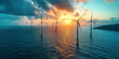 Renewable power: lines of offshore wind turbines against a beautiful sunset on sea