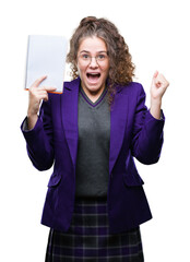 Wall Mural - Young brunette student girl wearing school uniform holding a notebook over isolated background screaming proud and celebrating victory and success very excited, cheering emotion