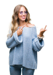 Wall Mural - Beautiful young blonde woman wearing sunglasses over isolated background smiling and looking at the camera pointing with two hands and fingers to the side.