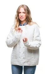 Poster - Beautiful young blonde woman wearing winter sweater over isolated background disgusted expression, displeased and fearful doing disgust face because aversion reaction. With hands raised