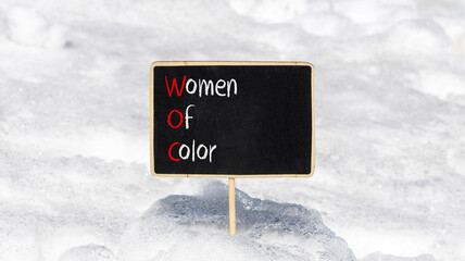 Wall Mural - WOC women of color symbol. Concept words WOC women of color on beautiful yellow blackboard. Beautiful white snow background. Business WOC women of color social issues concept. Copy space.