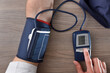 Man taking his blood pressure with a digital meter top