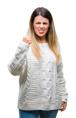 Wall Mural - Young beautiful woman casual white sweater over isolated background angry and mad raising fist frustrated and furious while shouting with anger. Rage and aggressive concept.