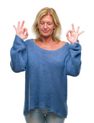 Sticker - Middle age blonde woman wearing winter sweater over isolated background relax and smiling with eyes closed doing meditation gesture with fingers. Yoga concept.