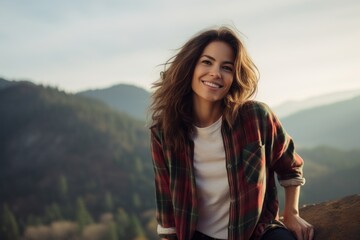Wall Mural - Portrait of a cheerful woman in her 30s wearing a comfy flannel shirt in front of panoramic mountain vista