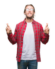 Sticker - Young handsome man with long hair wearing glasses over isolated background smiling crossing fingers with hope and eyes closed. Luck and superstitious concept.