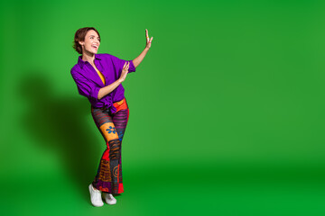 Sticker - Photo portrait of old vintage outfit woman in purple stylish shirt trendy pants with good mood dancing isolated on green color background