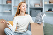Young Woman Unpacking Clothes, Expressing Disappointment Over Fashion Purchase In Modern Living Room, Returns And Exchanges Concept