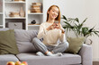 Young Woman Enjoying Social Media On Smartphone In Cozy Living Room, Comfortable Home Leisure With Technology, Happy Smiling, Casual Style