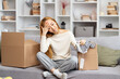 Young Woman Feeling Overwhelmed While Unpacking Boxes In Living Room, Expressing Exhaustion, Stress And Moving House Fatigue. Concept Of New Home And Personal Challenges.