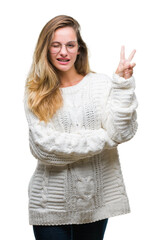 Sticker - Young beautiful blonde woman wearing winter sweater and sunglasses over isolated background smiling with happy face winking at the camera doing victory sign. Number two.