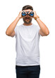 © Krakenimages.com - Young handsome man looking through binoculars over isolated background with a confident expression on smart face thinking serious