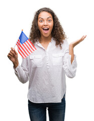 Wall Mural - Young hispanic woman holding flag of United Estates of America very happy and excited, winner expression celebrating victory screaming with big smile and raised hands