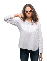 Poster - Young hispanic woman wearing sunglasses with angry face, negative sign showing dislike with thumbs down, rejection concept