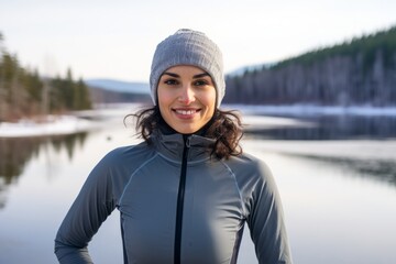 Wall Mural - Portrait of a satisfied woman in her 30s sporting a breathable mesh jersey over backdrop of a frozen winter lake