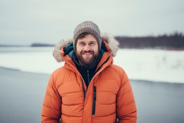 Wall Mural - Portrait of a glad man in his 30s donning a durable down jacket isolated on backdrop of a frozen winter lake