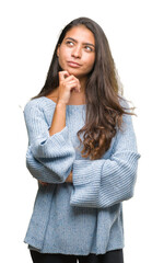 Canvas Print - Young beautiful arab woman wearing winter sweater over isolated background with hand on chin thinking about question, pensive expression. Smiling with thoughtful face. Doubt concept.