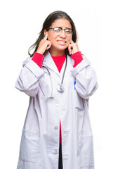 Sticker - Young arab doctor woman over isolated background covering ears with fingers with annoyed expression for the noise of loud music. Deaf concept.